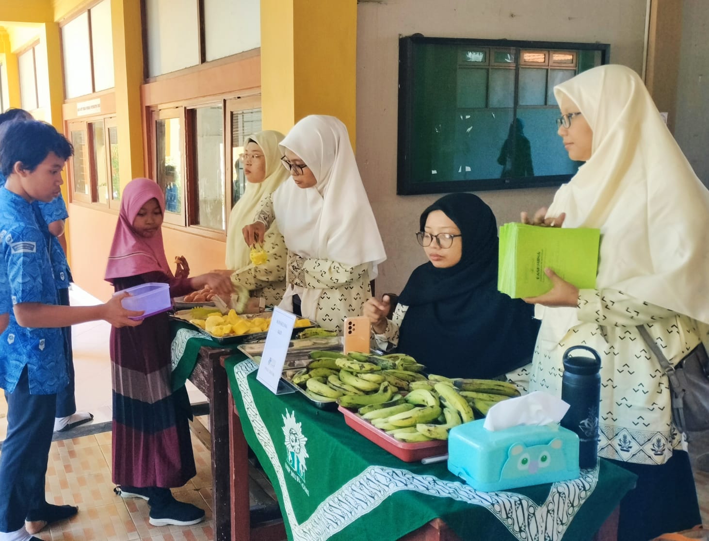 Para kader Nasyiah dari PCNA Kebomas membantu pemberian real food berupa pisang, singkong dan telur rebus di Pos Gizi. (Tagar.co/Sayyidah Nuriyah)