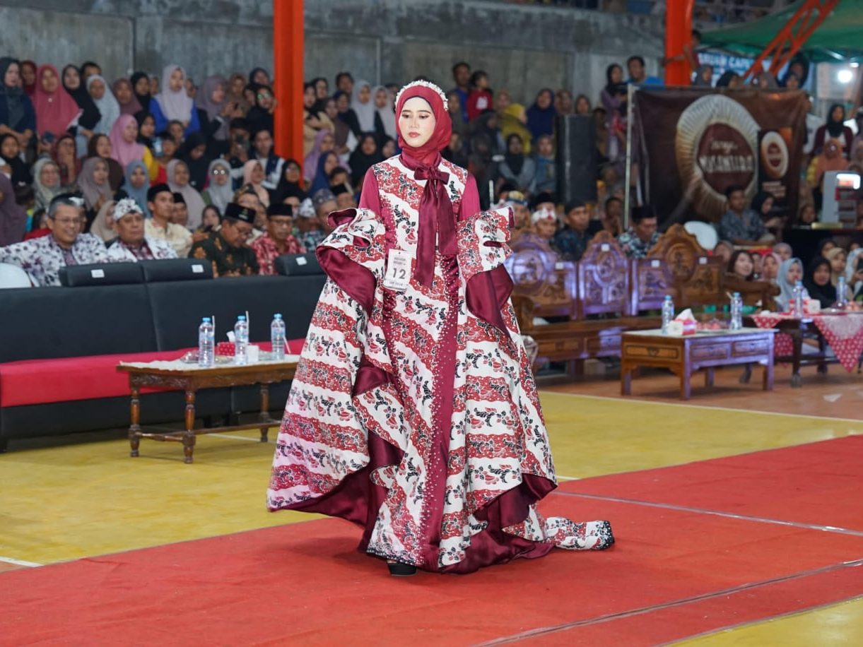 Najwa Fauzus Sa’aadah tak pernah menyangka, even lomba pertamanya dalam Sendangagung Batik Fashion 2024 berbuah manis. Gaun rancangan ibu satu anak alumnus Ponpes Al-Ishlah itu berhasil menyabet juara.

Tagar.co – Sendangagung Batik Fashion (SBF) yang digelar Pemdes Sendangagung, Paciran, Lamongan, itu masih menyisakan kesan mendalam bagi Najwa Fauzus Sa’aadah. Dua gaun hasil rancangan alumnus Ponpes Al-Ishlah tahun 2014 tersebut berhasil meraih juara.

Ibu satu anak asli Sendangagung itu tak menyangka, SBF yang dihadiri Camat Paciran H. Sami’an MM, anggota DPRD Lamongan, dan juga Bupati Dr H Yuhronur Efendi, itu menjadi even pertamanya yang berbuah manis.

Gaun-gaun hasil rancangan Faza—panggilan Najwa Fauzus Sa’aadah—berhasil menjadi juara II dan harapan II pada ajang yang berlangsung di Watungkal Edupark Sendangagung (WES) Kamis-Sabtu (18-20/7/2024).

Para penonton yang hadir tidak hanya dari Sendangagung, juga dari tetangga desa  seperti Kecamatan Paciran dan Solokuro. Lomba Fashion SBF tingkat SMA berlangsung pada Jumat (19/7/24) malam. Untuk kategori umum sekaligus launching motif batik baru berlangsung pada Sabtu (20/7/24). Partisipan acara tersebut beragam, mulai dari Lamongan, Bojonegoro, hingga Surabaya.

Bagi Faza, even SBF menjadi pengalaman lomba pertamanya mendesain baju. Dia bersyukur dapat meraih dua gelar, yakni juara kedua dan harapan II. Baginya, hal tersebut menjadi kebanggaan tersendiri. “Karena saingannya berasal dari berbagai daerah,” tutur lulusan D3 Tata Busana Universitas Negeri Surabaya (Unesa) tersebut.

Baca juga: Pembantu Warung Soto Itu Bisa Kuliahkan Anaknya di UGM

Gaun dengan batik motif Batik Khas Lamongan (BKL) karya Najwa Fauzus Sa’aadah di  Sendangagung Batik Fashion  2024. (Tagar.co/Sri Asian)

Utusan Desa

Pada lomba Fashion Show tingkat SMA, gaun rancangan Faza dibawakan Yuk Lamongan Stephaney Dewantari berhasil meraih juara II se-Kabupaten Lamongan. Busana pertama yang dibuatnya itu atas nama utusan desa untuk mengikuti acara launching motif batik baru Sendangagung.

Ada tiga motif yang  di-launching seperti motif batik Rahayuning, Rontal, hingga Sego Langgi. “Busana yang saya buat ini menggunakan kain batik motif Rontal,” ungkapnya.

Menurut filosofinya, Rontal diambil dari bahasa jawa  “ron” yang berati daun, dan “tal” dari kata ental atau siwalan, sesuai dengan kegunaan daun ental yang multifungsi. “Harapannya, batik tidak hanya difungsikan sebagai sarung atau jarik (kain dengan motif aneka batik), tapi bisa dimodifikasi menjadi gamis, mukena, aksesoris, gaun pengantin, serta aneka macam kerajinan tangan dan lain lain,” paparnya.

Pada dasarnya daun siwalan berbentuk seperti kipas. “Selain daun siwalan, juga mengusung ikon Lamongan lainnya seperti ikan bandeng dan lele dengan inovasi terbaru,” jelas putri pasangan Sukaryudi (almarhum) dan Linsiana tersebut.

Gaun rancangan Faza ditampilkan dengan siluet mermaid dengan dominasi kain batik, duches, dan tulle bridal. Busana juga dihiasi rangkaian payet secara menyeluruh. Pada bagain dada dihiasi payet rantai secara menjalar sampai belakang sebagai center of interest. “Sehingga busana yang saya buat ini tampak kelihatan mewah dan elegan,” jelasnya.

Menurut desain batiknya, Rontal memberi pesan tersirat agar generasi muda dapat menjaga alam, budaya, dan melestarikan batik. “Untuk durasi pengerjaan membuat busana ini membutuhkan waktu sekitar 6 hari,” paparnya.

Gaun dari batik motif Rontal rancangan Najwa Fauzus Sa’aadah di  Sendangagung Batik Fashion 2024. (Tagar.co/Sri Asian)

Bermanfaat bagi Sesama

Faza kemudian menceritakan gaun rancangannya kedua, yang dikenakan model Hamidatul Istiqomah Mustahad. Busana tersebut menggunakan kain motif Batik Khas Lamongan (BKL)—motif ini biasa digunakan untuk jarit pada busana wanita. “Tapi untuk kali ini saya bikin dalam bentuk gaun,” ujarnya.

Durasi pengerjaan busana yang sangat singkat, yakni hanya dalam waktu tiga hari sebelum hari H, sehingga membuatnya harus memutar otak. “Saya berpikir, bagaimana caranya agar busana ini pengerjaanya tidak menghabiskan waktu yang lama, tapi nanti hasilnya tetap menarik,” terangnya.

Dia kemudian menemukan inspirasi desain yang sesuai, tapi membutuhkan bahan yang tidak sedikit. Busana tersebut dibuat menggunakan siluet mermaid yang didominasi kain batik dan kain maxmara silk.

Pada bagian badan depan busana dihiasi sedikit rangkaian payet agar menambah nilai glamour. Sedangkan pada lengannya dibuat dalam desain ruffle sebagai center of interest. “Sehingga desain busana yang saya buat tampak simpel, tapi tetap terlihat menarik dan glamour,” kata ibu dari Shezan Syazwina Eleanor tersebut.

Faza yang kesehariannya berprofesi sebagai penjahit ini  merasa bersyukur diterima di Jurusan Tata Busana Unesa Surabaya, karena pasca lulus kuliah langsung bisa mengamalkan ilmu dan bisa cari uang sendiri. Menjadi penjahit bisa menciptakan lapangan kerja, walau sekarang baru punya dua asisten,” jelas istri Afkarul Azka yang juga asli Sendangagung itu.

Faza juga berharap dapat memberi kontribusi positif terhadap kemajuan desa Sendangagung, yang menurutnya tiap hari semakin bersinar. “Tidak hanya di tingkat  Kabupaten Lamongan tapi juga tingkat provinsi,” kata perempuan dengan prinsip sebaik-baik manusia adalah yang paling bermanfaat untuk sesama tersebut. (#)

Jurnalis Sri Asian Penyunting Darul Setiawan.