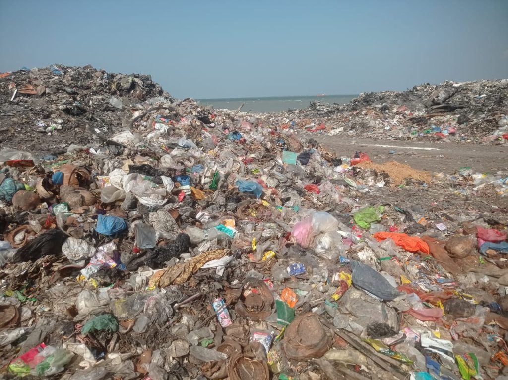 Sampah menggunung di tepi laut Desa Campurejo, Panceng, Gresik. Setiap hari, warga disuguhi pemandangan yang tak sedap: gunungan sampah yang seolah hidup, berkembang biak dengan cepat, dan sesekali menyemburkan asap tebal.