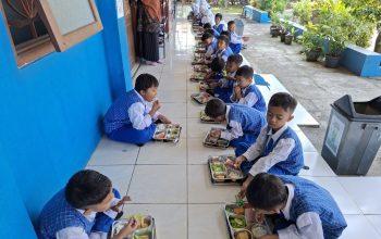 MBG MI Islamiyah Mojopetung, siswa antusias makan bersama. Menunya lengkap nasi, buah, sayur, tahu, dan nugget. Sebelum makan, para siswa berdoa dan diarahkan membuang sampah pada tempatnya